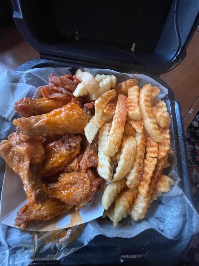 A wing restaurant's own phone photo of wings and fries in a takeout box, before and after enhancement with MenuPhotoLab (before)
